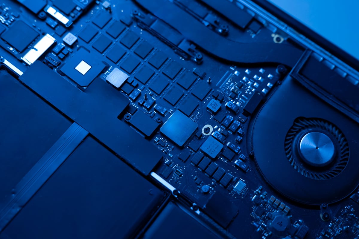 Disassembled laptop with exposed circuit board and components before repair