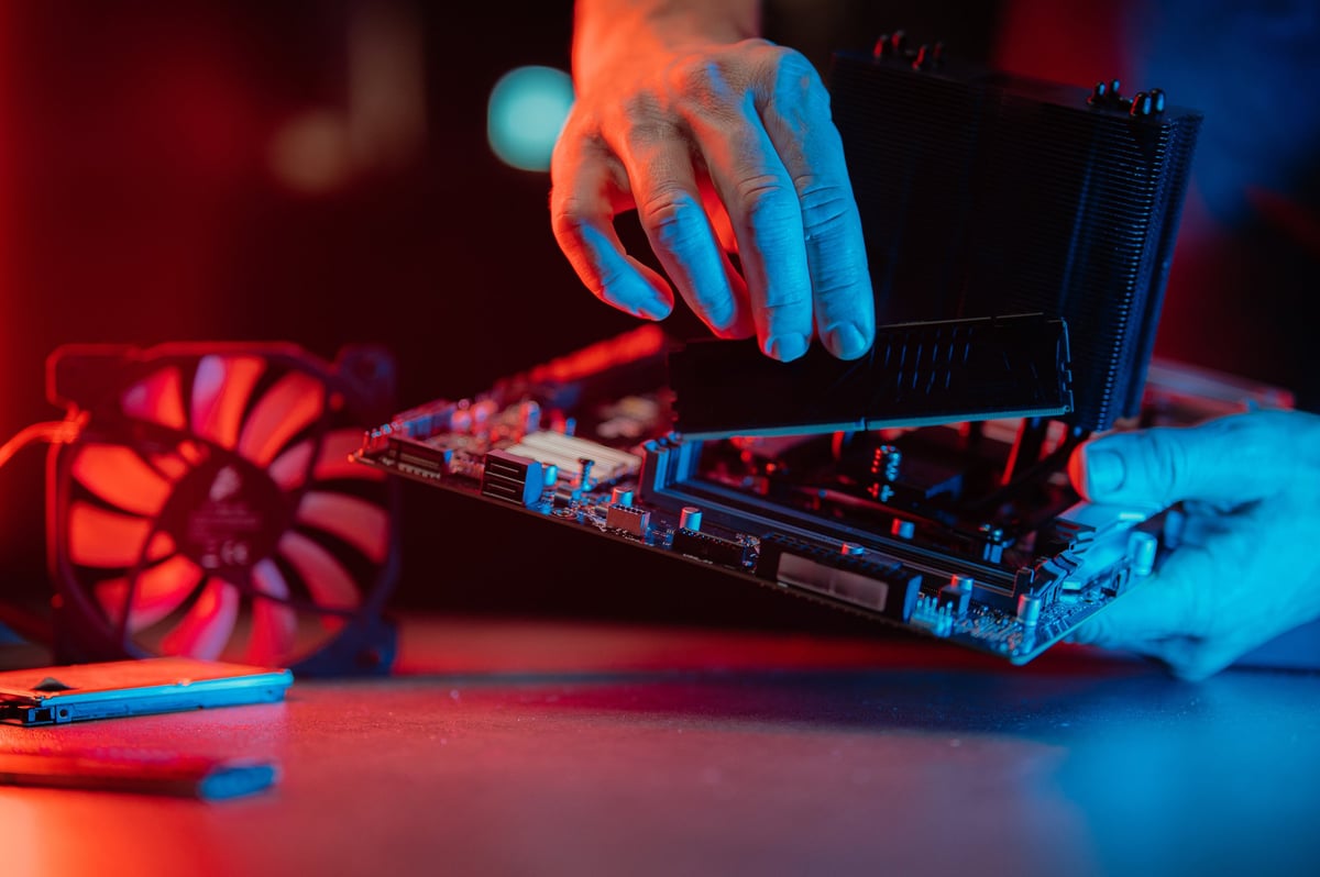 Technician installing a high performance DDR5 memory module into a computer motherboard during a RAM upgrade