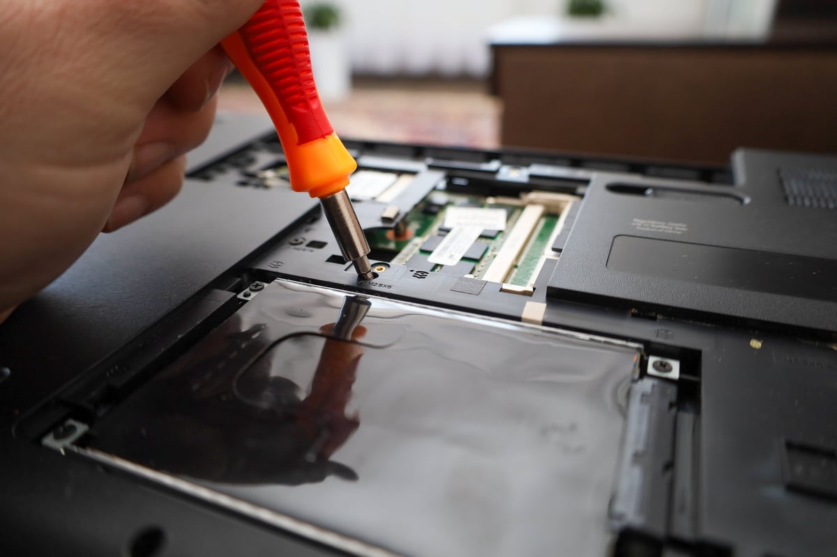 Technician carefully reassembling laptop components during precision repair service
